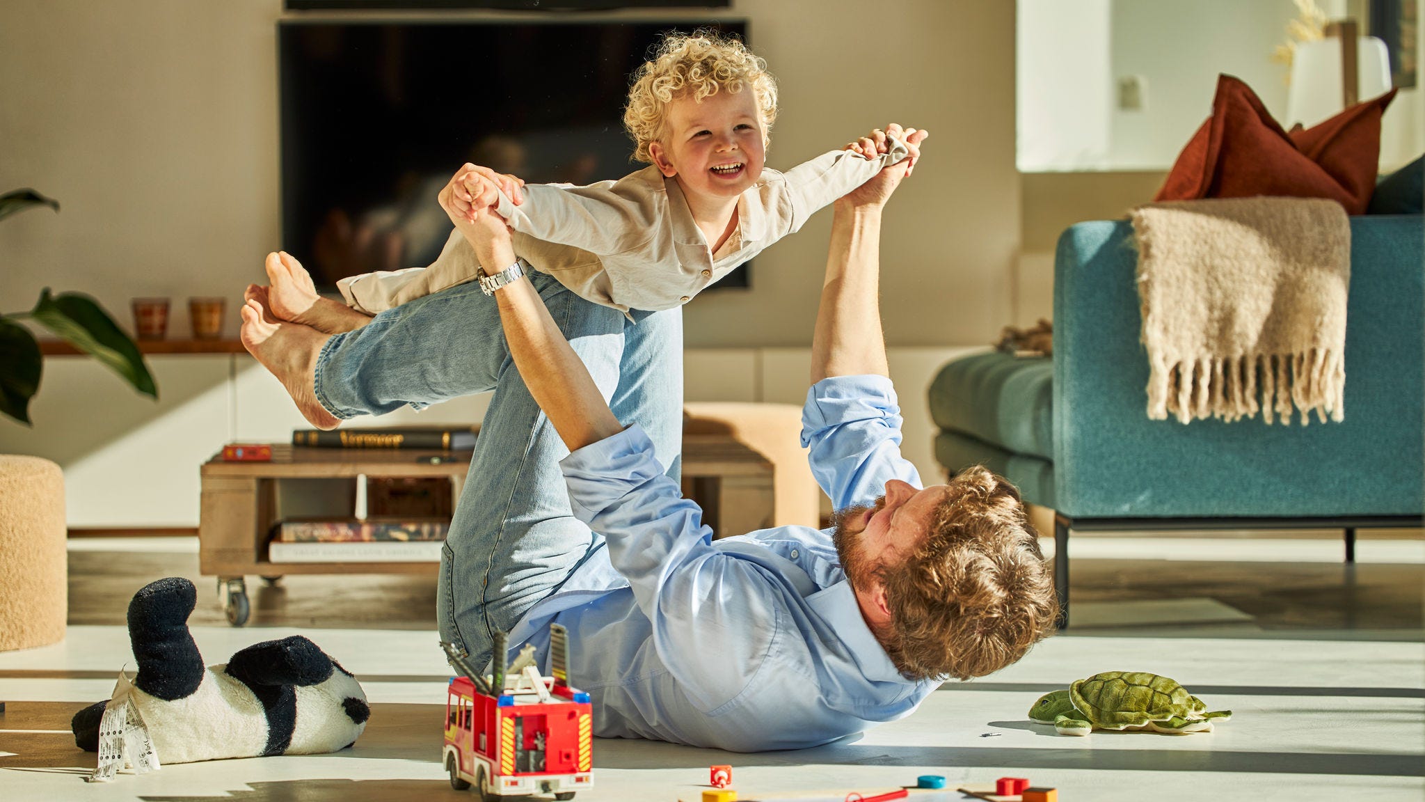 Баща и детето му щастливо си играят и се наслаждават на топлината на подовото отопление