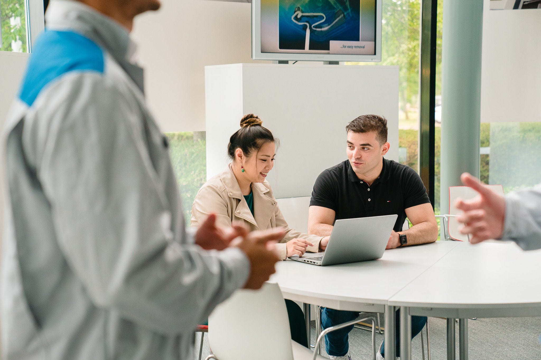 Жена, обясняваща нещо на мъж посредством лаптопа си