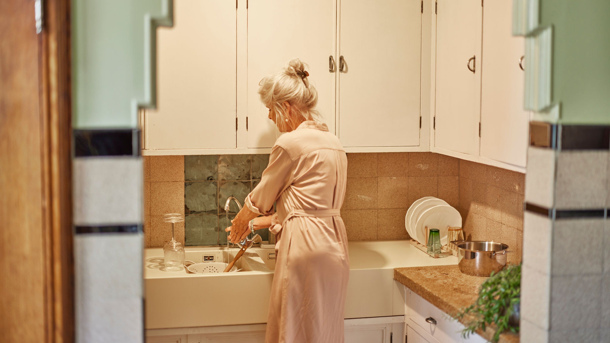 Жена, която мие съдове с топла вода от система Мулти сплит