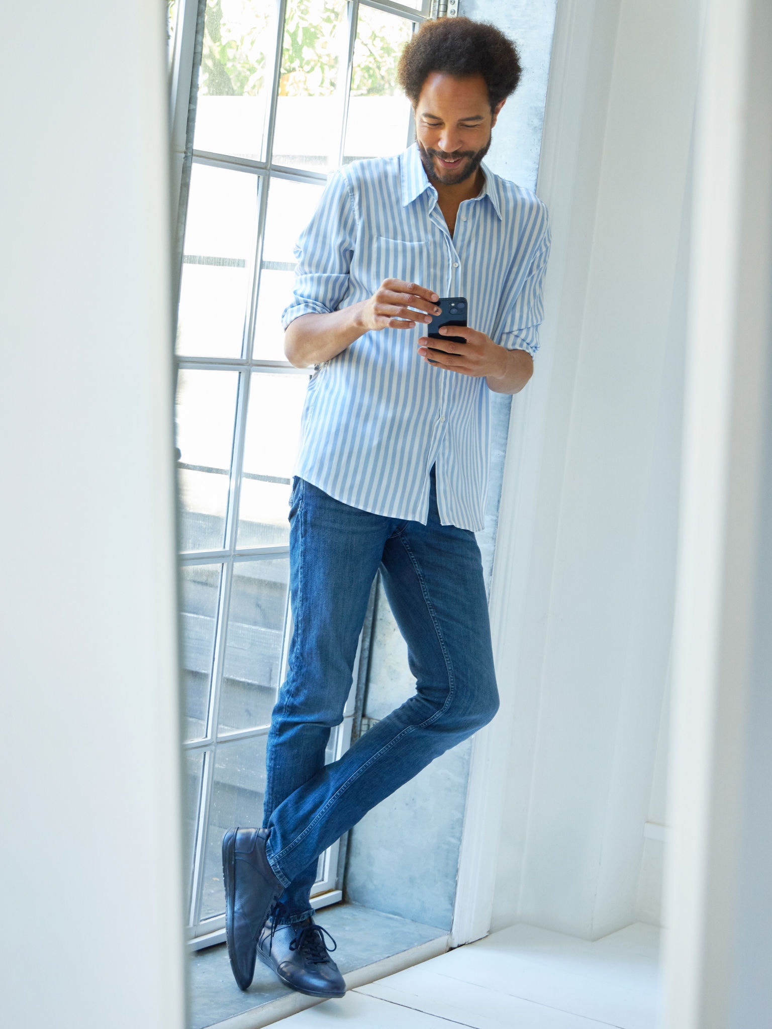 Мъж седи близо до прозорец и разглежда климатици на своя таблет във Virtual Experience Center