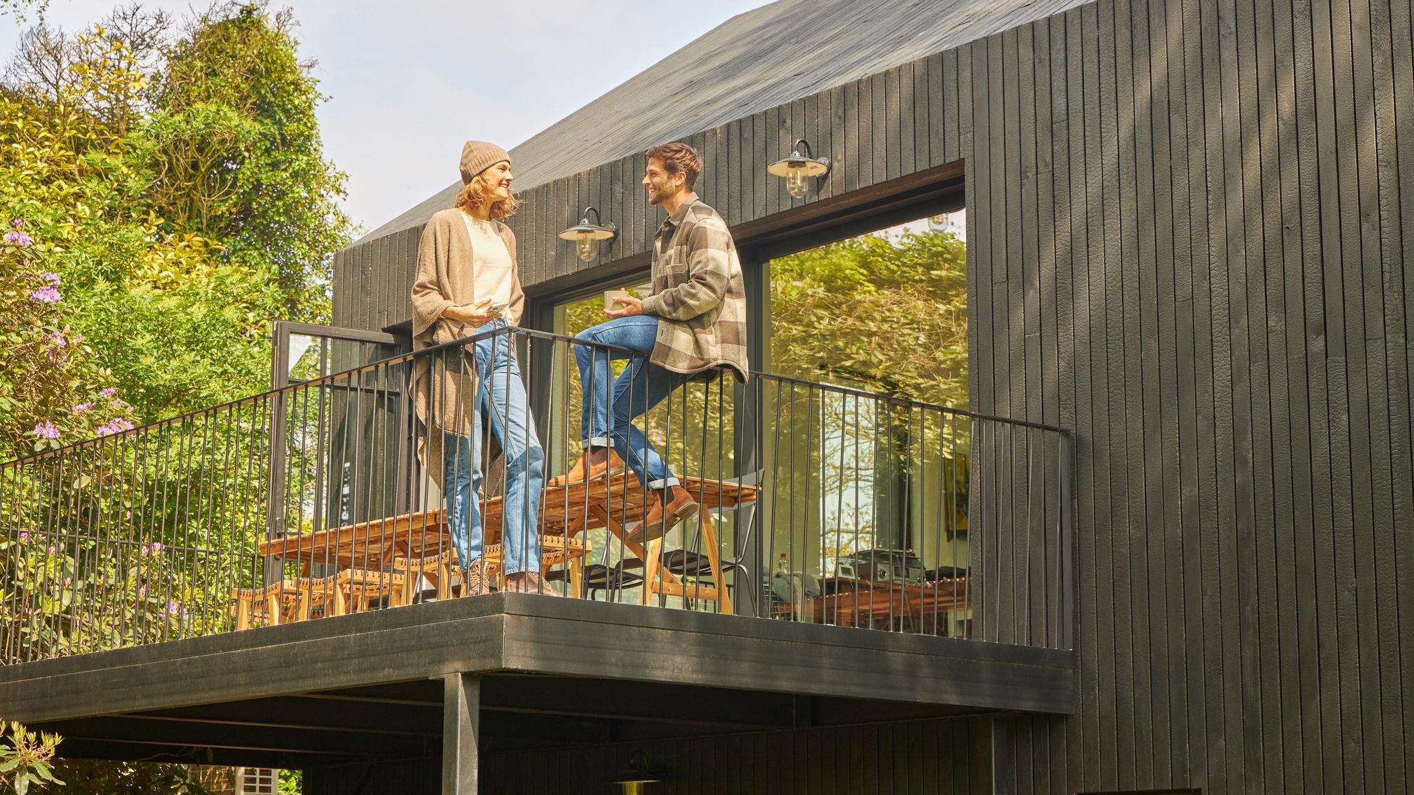 Семейна двойка обсъжда на терасата на бунгало сред природата