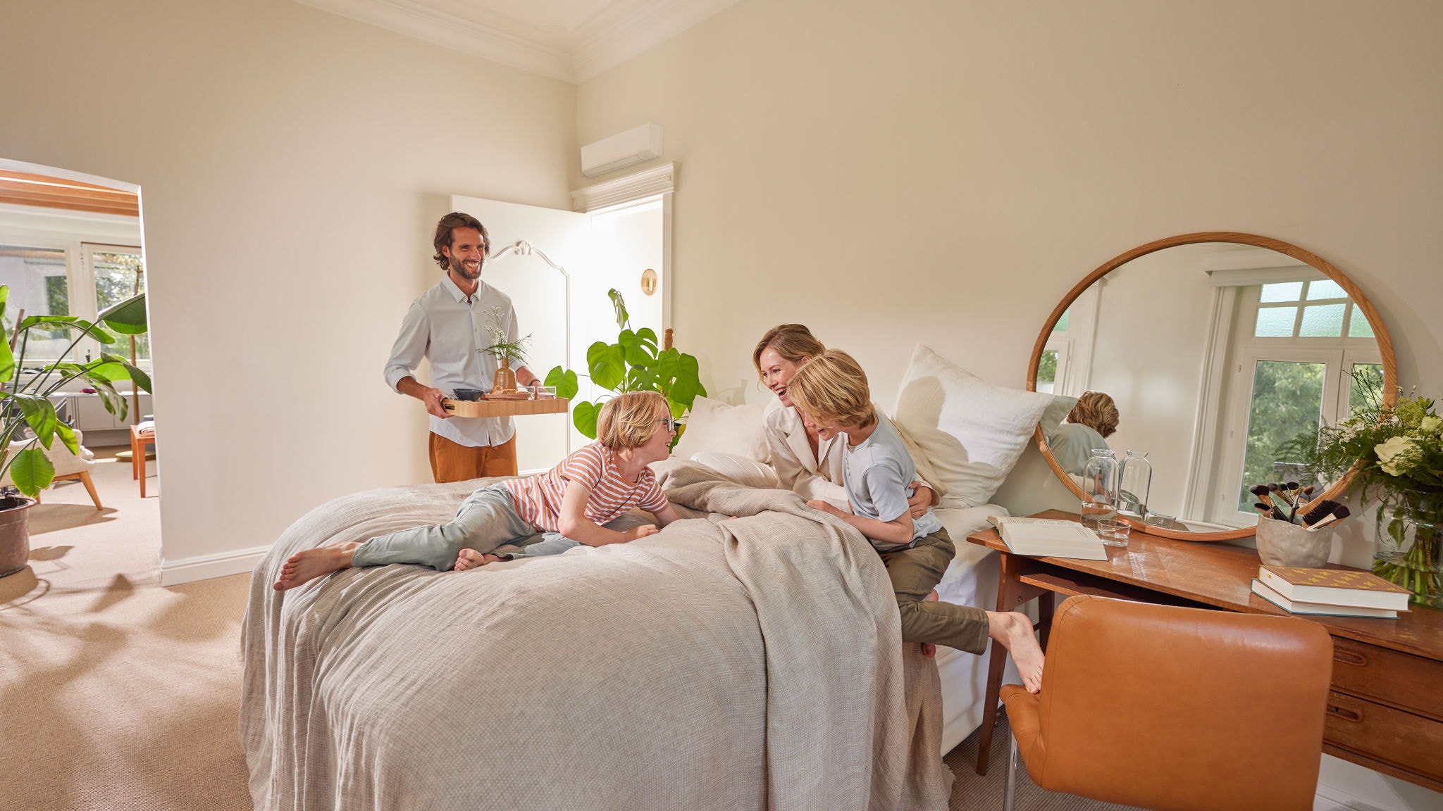 Семейство се наслаждава на уютен момент в спалня с хибридна термопомпа, монтирана на стената