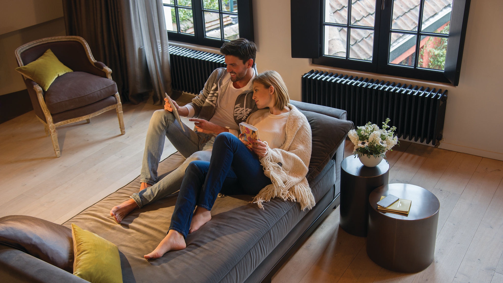 Двойка, релаксираща на дивана и гледаща нещо на таблет